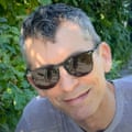 a man smiles while wearing sunglasses