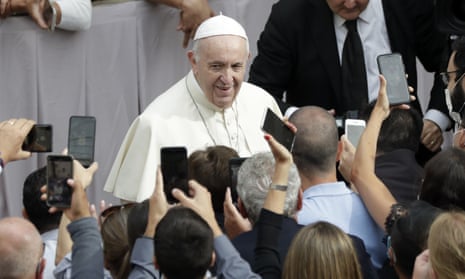 People hold up their phones and crowd towards Pope Francis