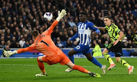 Arsenal's Leandro Trossard chips the ball over Brighton's keeper Bart Verbruggen for their third goal.