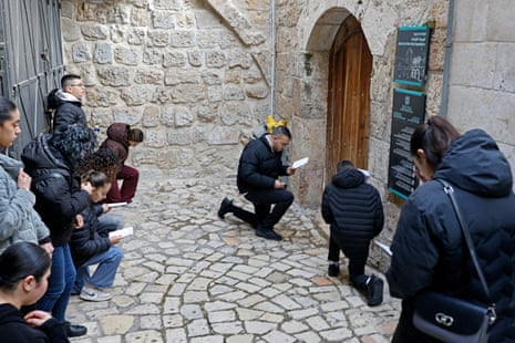 About a dozen Christian pilgrims kneel in prayer in front of the closed door of the Church of the Holy Sepulchre in the Old City of Jerusalem.