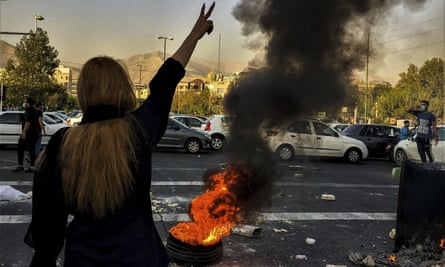 Woman making V gesture by burning fire in a Tehran street.