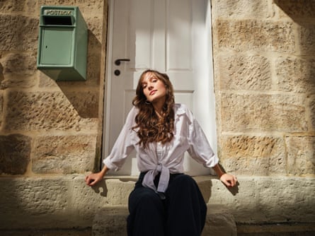 Gretta Ray sitting on sandstone steps in front of a white door