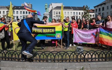 People gather in a square holding flags and banners