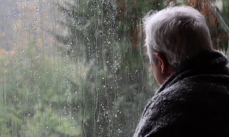 Man looking out of rainy window