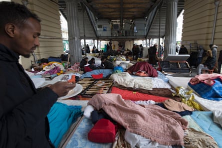A migrant eats at a makeshift camp in Paris near the Stalingrad subway station