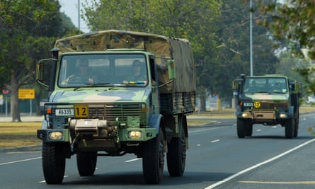 Military transport vehicles loaded with bottled water travel along a road in Bairnsdale, Victoria, on 4 January.