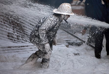 A firefighter is covered with aqueous film-forming foam (AFFF) as he tries to control a fire that broke out in a thinner manufacturing plant on the outskirts of Ahmedabad, India, 2018.