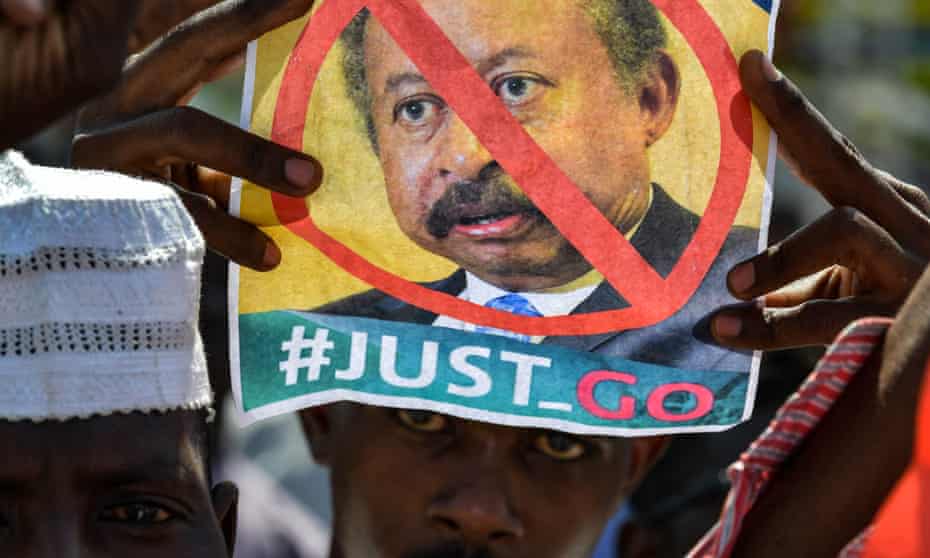 A Sudanese demonstrator raises a picture bearing a crossed-out face of prime minister Abdalla Hamdok