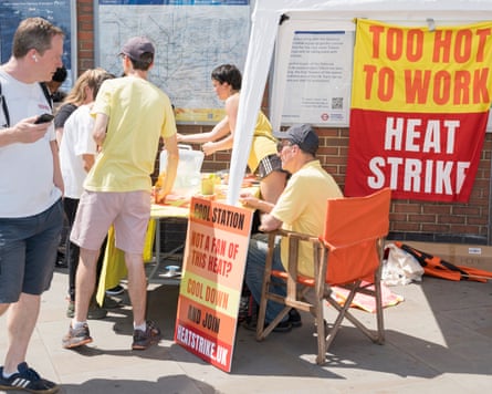 People sitting or standing around a table near a banner reading 'Too hot to work'