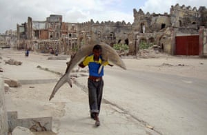  A man carries a shark through the streets of Mogadishu to take to the market. 