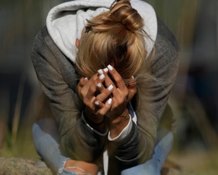 A woman sits outside with her head in her hands.