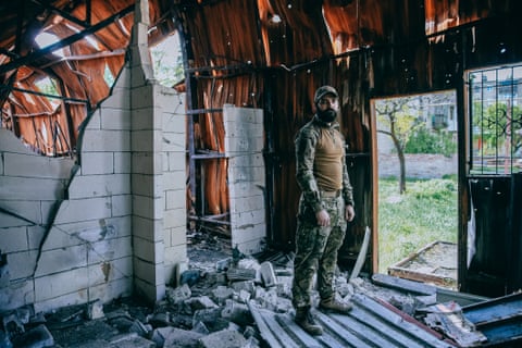 A soldier stands in a dilapidated building looking at the camera