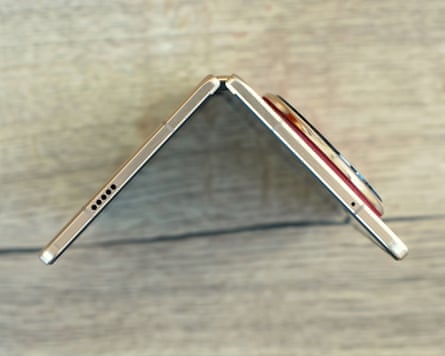 The Honor Magic V6 open at 90-degrees stood up on a wooden table.