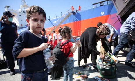 People receive food and water after disembarking from a vessel at the port of Heraklion on the island of Crete.