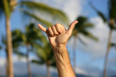A person making a hand gesture with the thumb and little finger extended and curling down the middle three fingers.