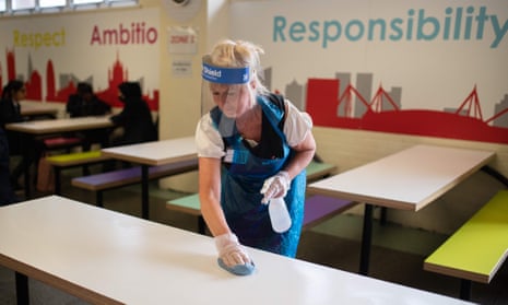 A cleaner wearing PPE sanitises furniture in the dining room of a school in Huddersfield, northern England.