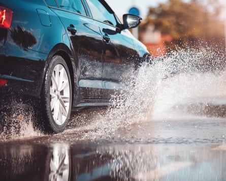 Car driving through the puddle and splashing by water.