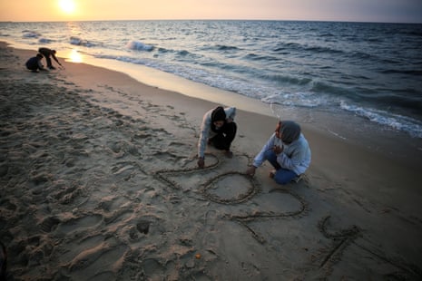 Palestinian girls are writing ''2024'' in the sand during the last sunset of the year in Deir al-Balah, in the central Gaza Strip, on December 31, 2023.
