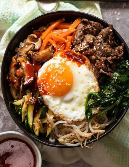 A packed bowl of bibimbap with beansprouts, bulgogi, mushrooms, carrots and a fried egg