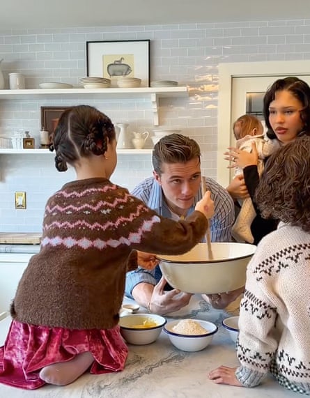 Nara Smith in her kitchen with her husband and three of her children, with the older child stirring a wooden spoon in a mixing bowl