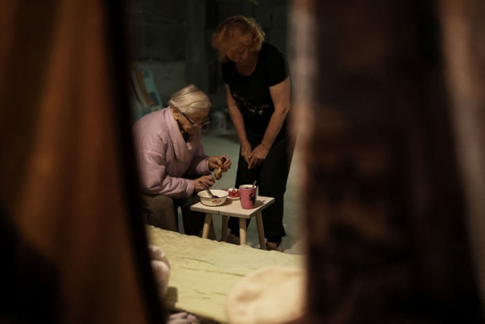 Former engineer Maria Nikolaevna, 92, eats as her daughter Natalya, 58, watches, inside a basement where they have lived since the beginning of the war, in northern Saltivka in Kharkiv.