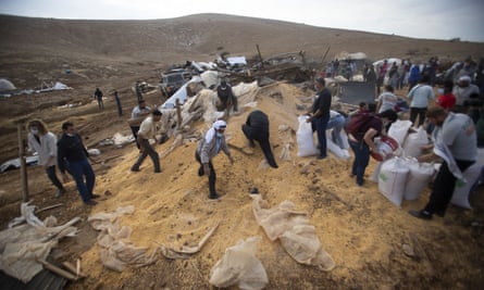 Palestinians collect grain after the Israeli army destroyed a storage structure in the West Bank.