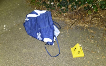 A blue shopping bag lying on a pavement with a small yellow marker cone next to it