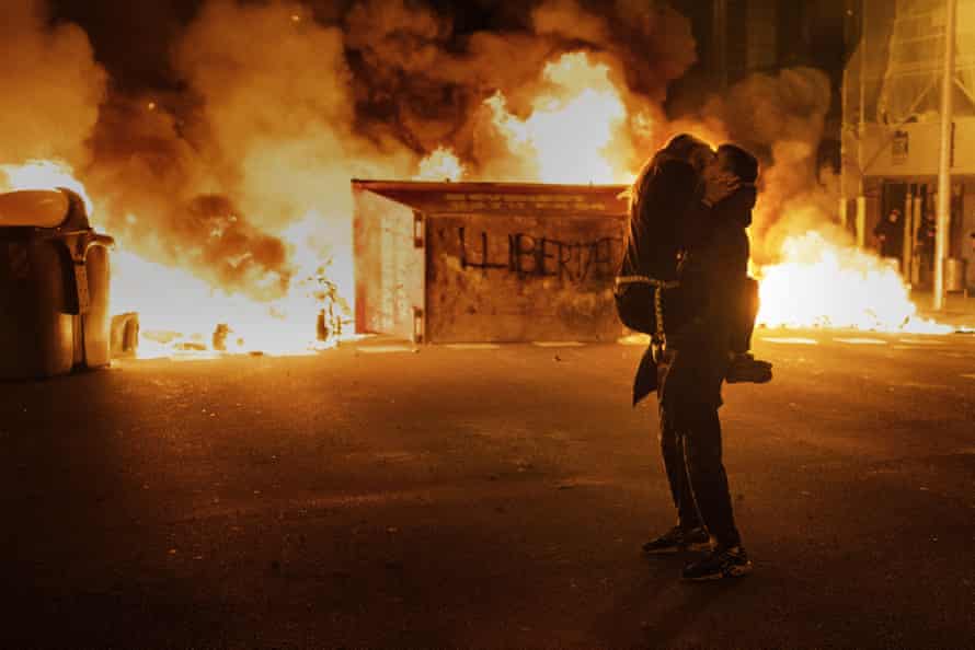 A couple kiss in front of a barricade set on fire by demonstrators during clashes with police following a protest condemning the imprisonment of rap singer Pablo Hasél in Barcelona, Spain on 18 February 2021.