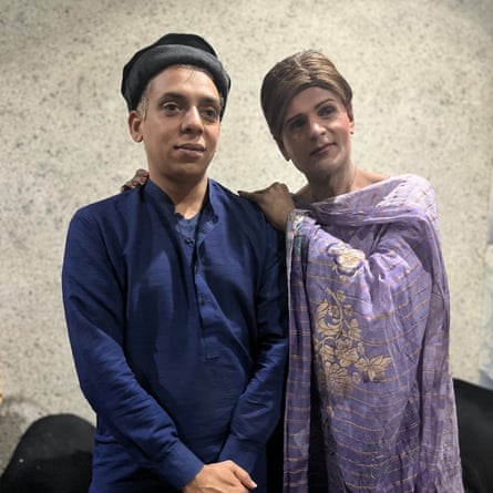 A woman dressed in purple with her arm round a person dressed in blue