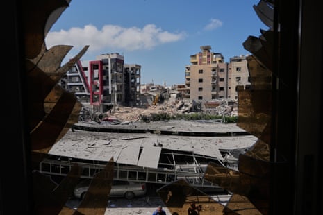 A destroyed building is seen through a shattered window.