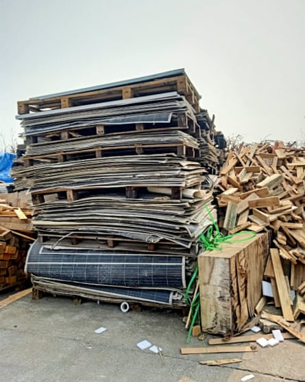 Wooden pallets with discarded solar panels and waste wood piled around them