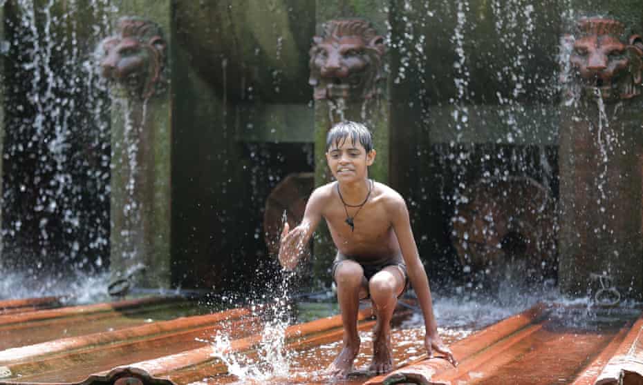 A boy plays in a fountain to cool off on a hot summer day in New Delhi.