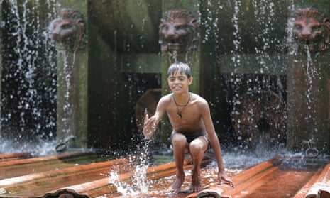 A boy plays in a fountain to cool off on a hot summer day in New Delhi.