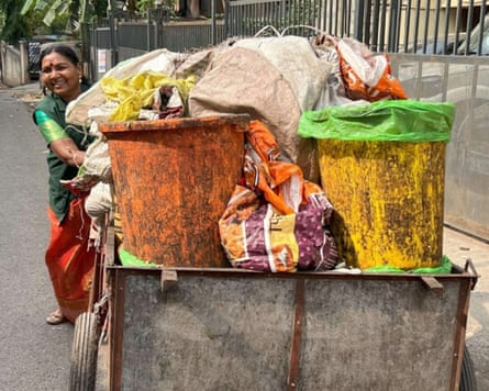 A woman pushing a cart laden with waste