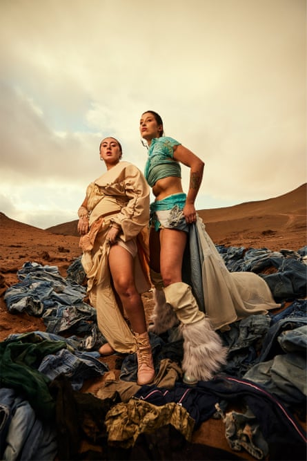 Two models dressed in clothes salvaged from a dump in Atacama desert pose among waste clothing