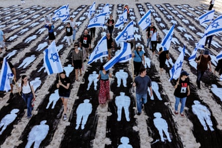 An installation on a beach with people walking through it holding Israeli flags.