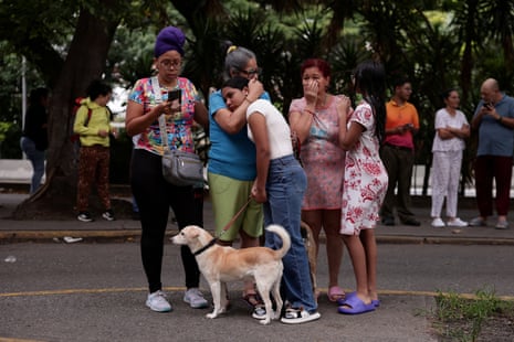 people stand on a street hugging each other with their dog