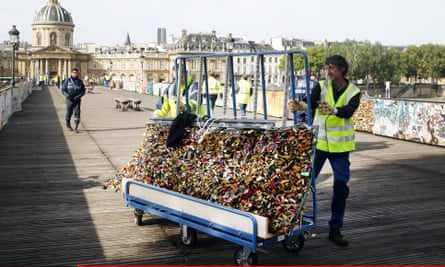 A council worker pushing a trolley of locks he has just removed from the Pont des Arts bridge