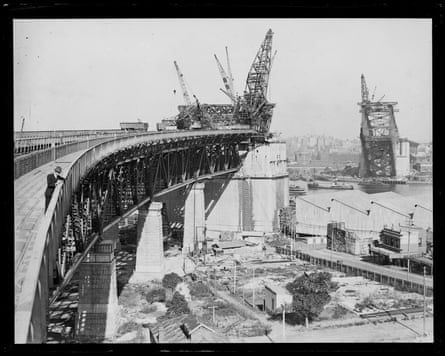Cranes positioned at both sides of the unfinished Sydney Harbour Bridge