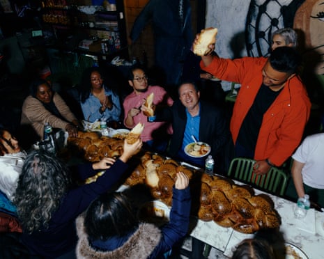 The New York City comptroller, Brad Lander (center), breaks challah bread on Shabbat.