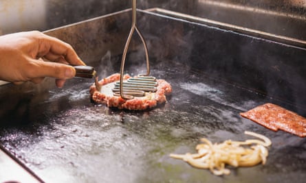man press beef patties with spatula on a griddle2XB1CXF man press beef patties with spatula on a griddle