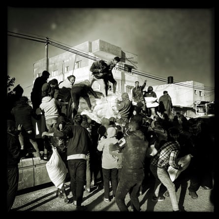 A crowd of people take food bags of food from vehicles
