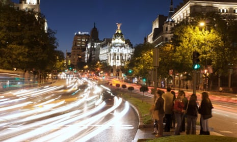 Cars pass through Madrid’s Gran Via, with the city hall in the background.