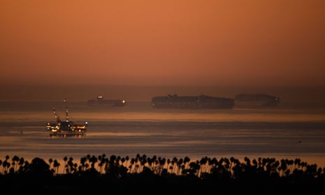 An oil platform stands offshore as cargo shipping container ships wait in the Pacific Ocean to enter the port of Los Angeles.