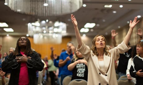 a woman raises her hands as she leads a room in prayer