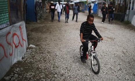 A boy rides his bicycle in the Calais migrant camp.
