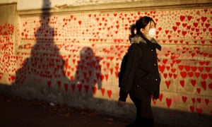 A person wearing a protective face mask walks past the Covid Memorial Wall in London, Britain.