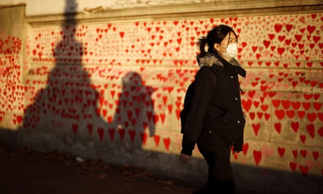 A person wearing a protective face mask walks past the Covid Memorial Wall in London, Britain.