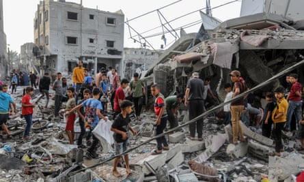 Groups of men and boys searching among wreckage and tangled buildings after airstrikes in Rafah, Gaza.