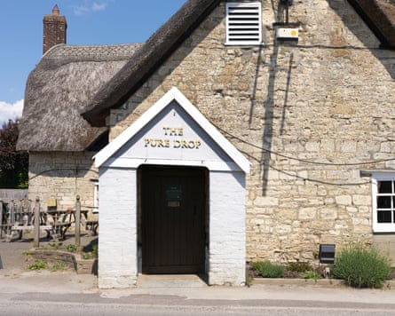 Thatched inn with stone front and 'the Pure Drop Inn' sign